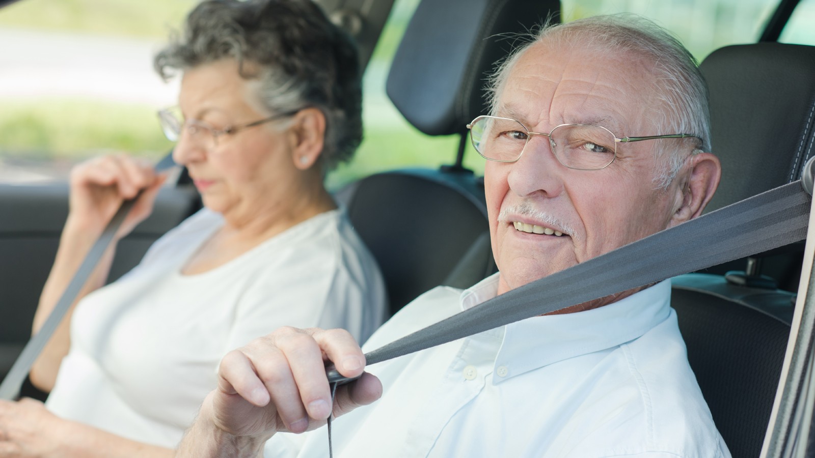 Elderly couple putting on their seatbelts
