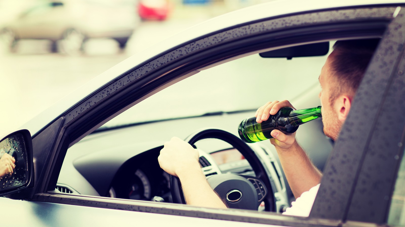 man drinking alcohol while driving the car