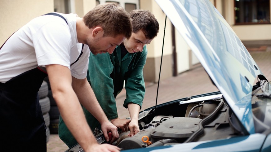 Two auto mechanics working with car