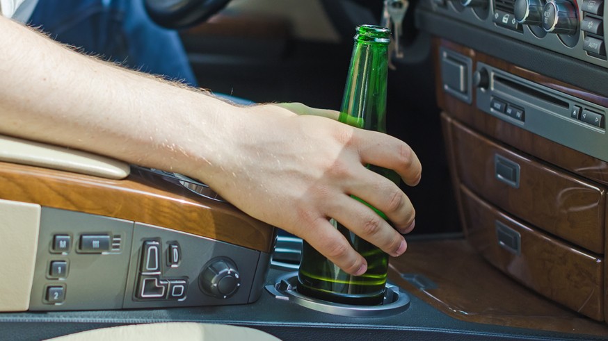 Driving Under the Influence. Male hand with bottle of beer.