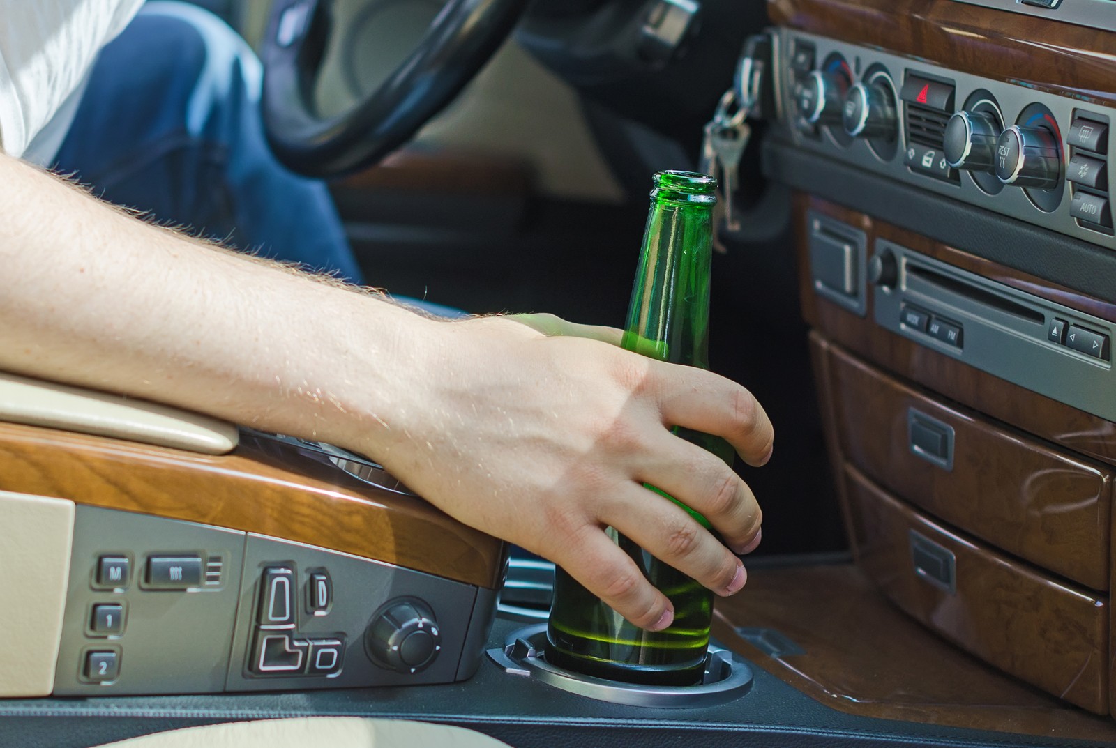 Driving Under the Influence. Male hand with bottle of beer.