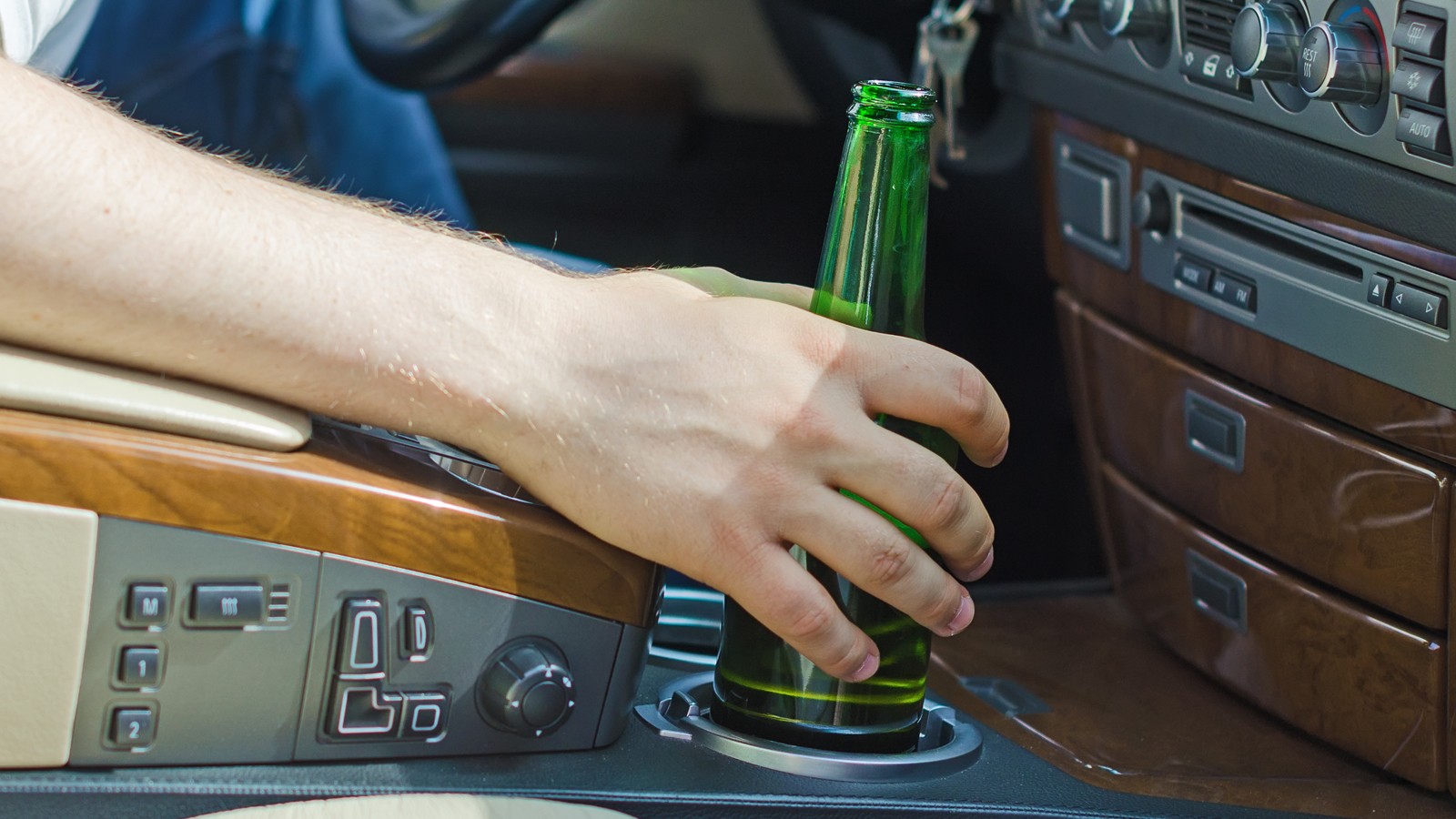 Driving Under the Influence. Male hand with bottle of beer.