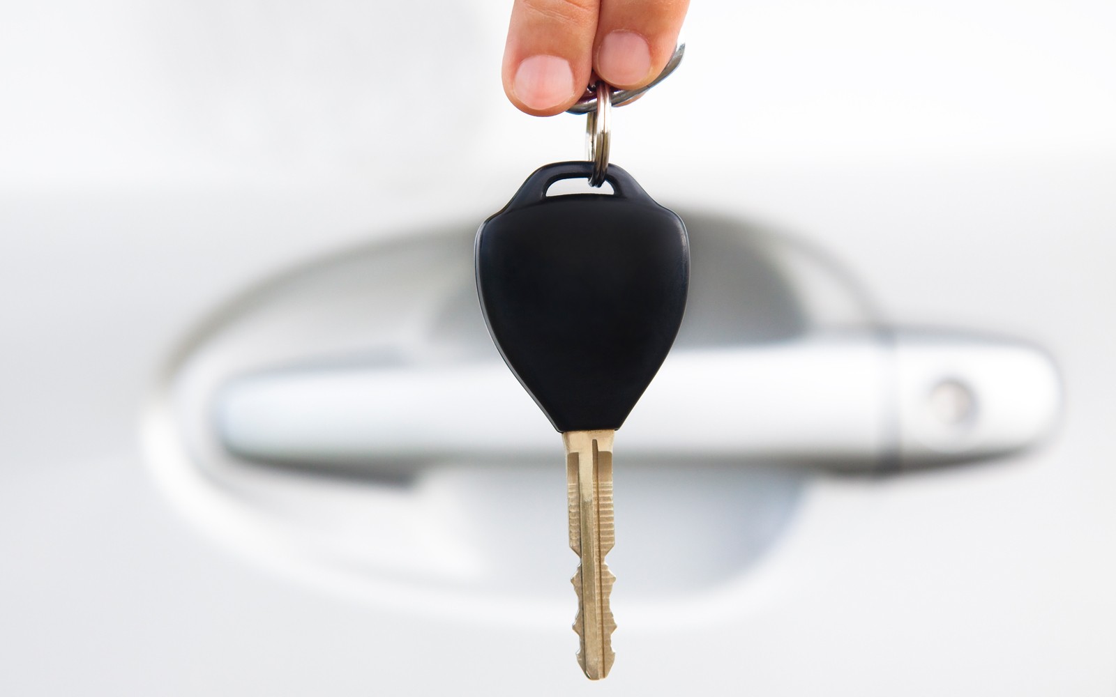 hand holding car key before door of car