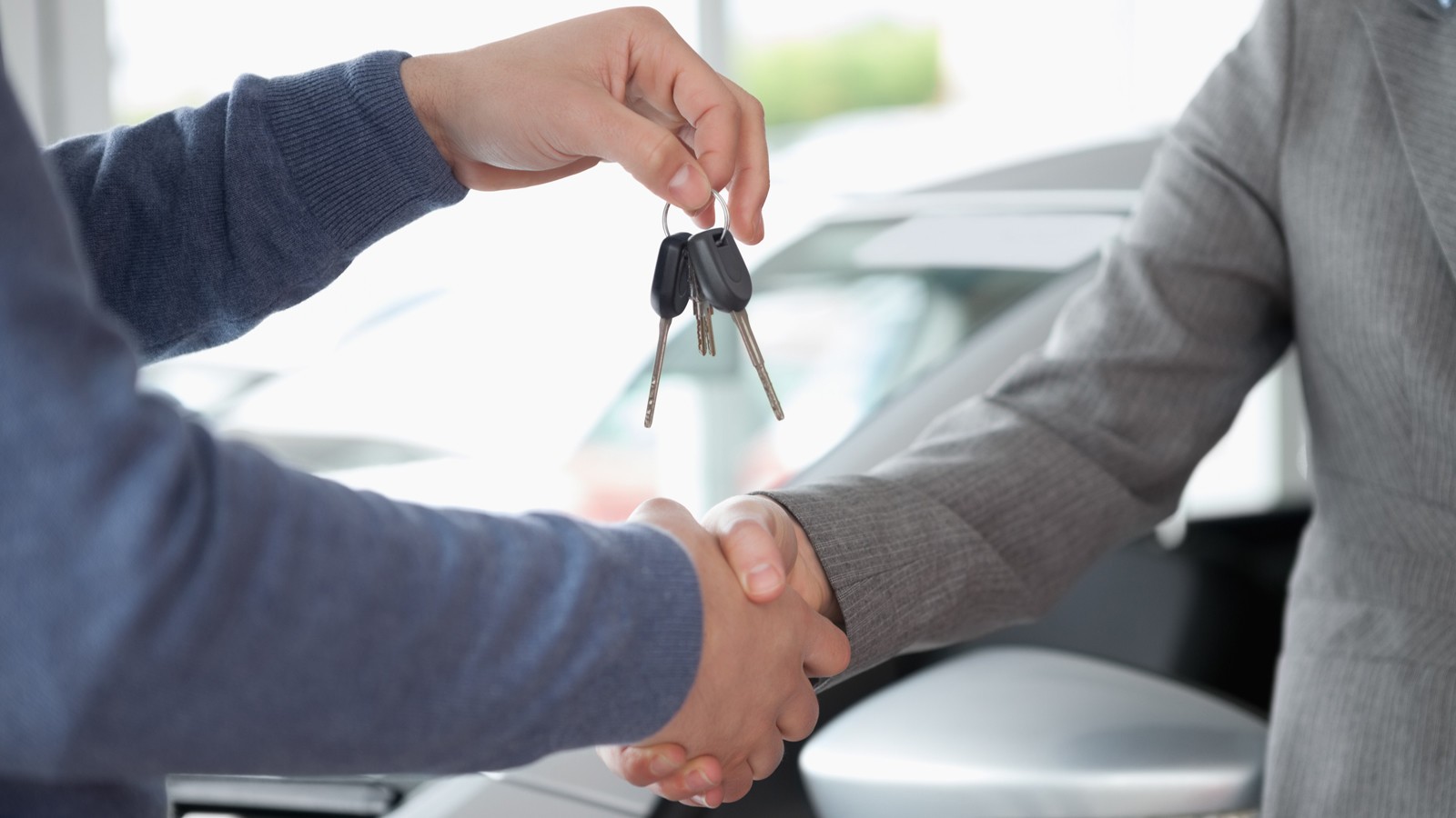 People shaking each other hands while holding keys