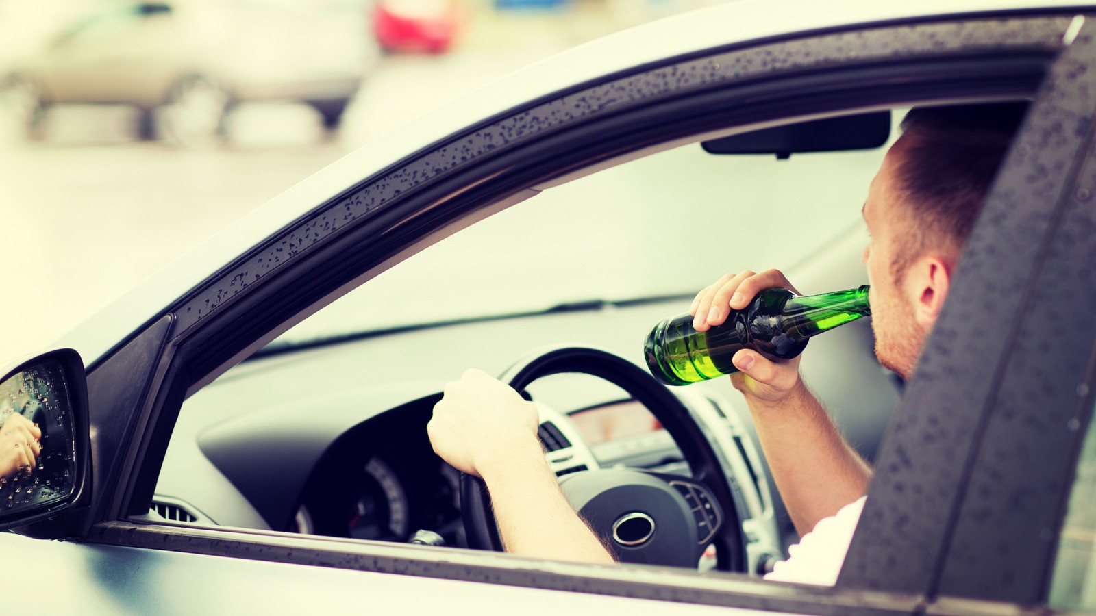 man drinking alcohol while driving the car