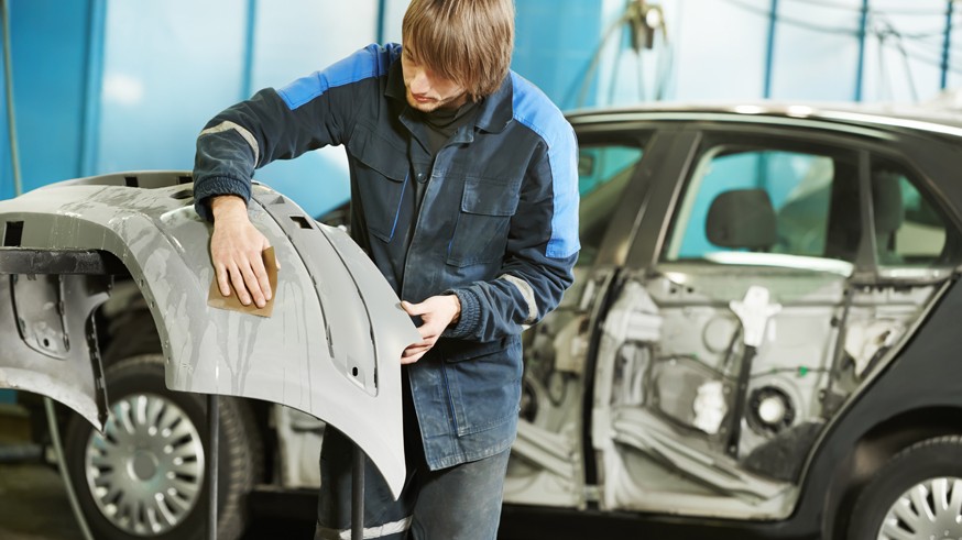 repairman sanding plastic car bumper