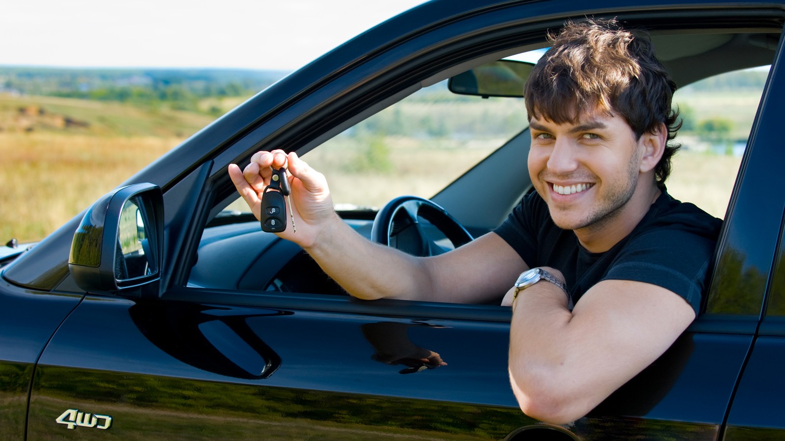 happy man showing keys in car