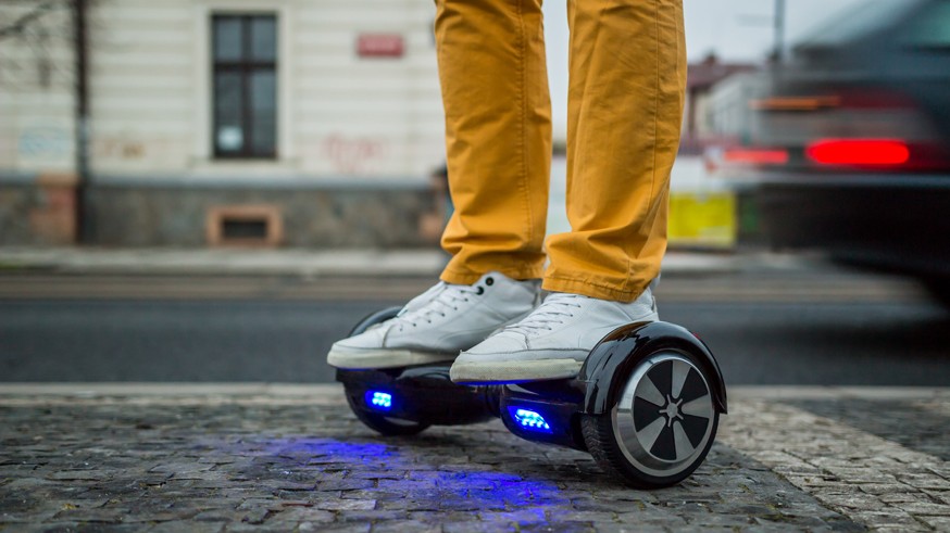 man is using hoverboard against the background of leaving car