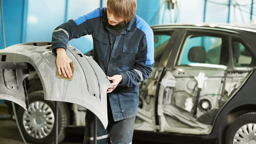 repairman sanding plastic car bumper