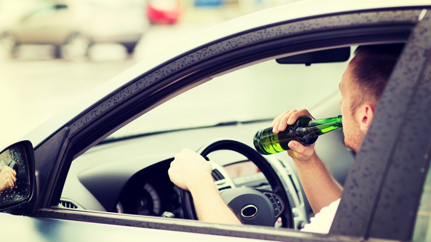 man drinking alcohol while driving the car