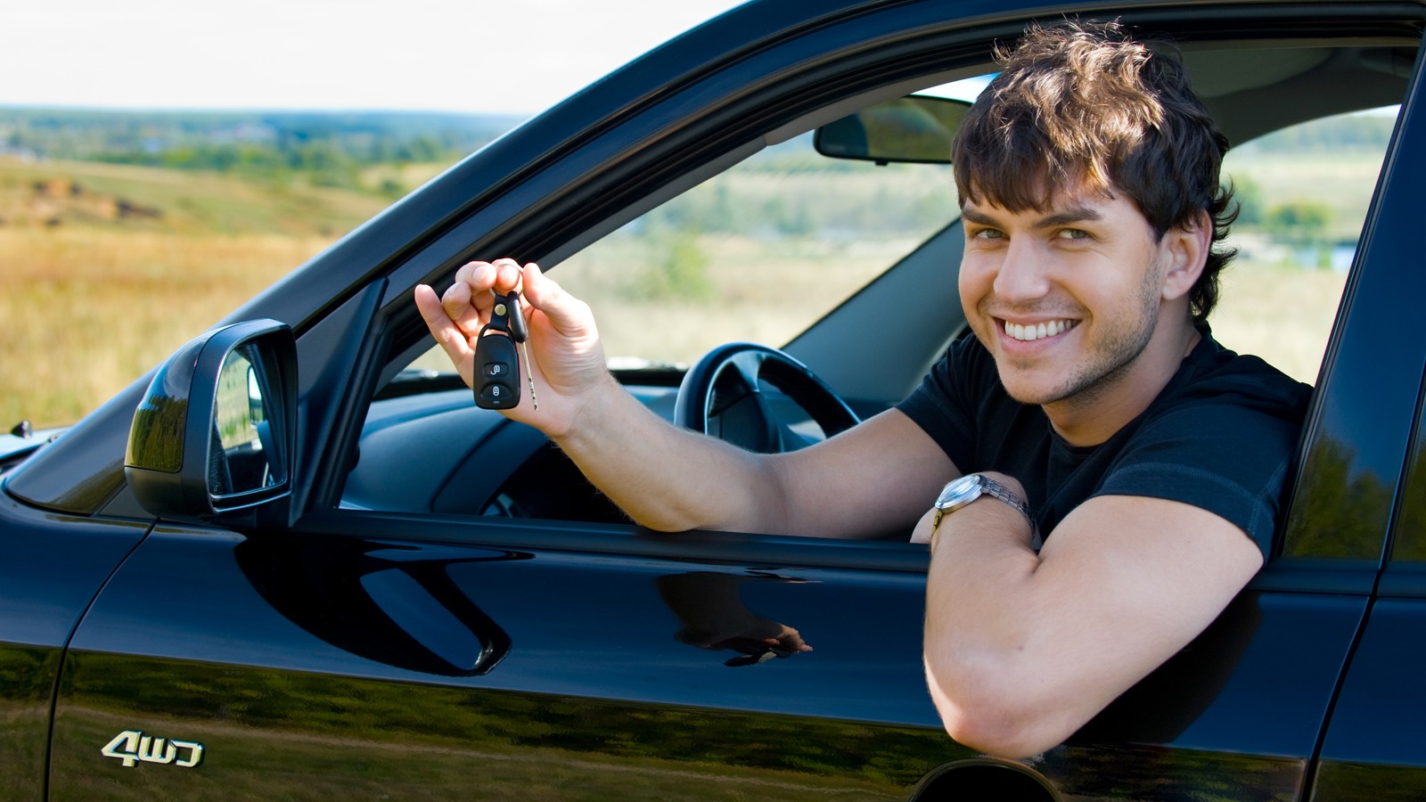 happy man showing keys in car