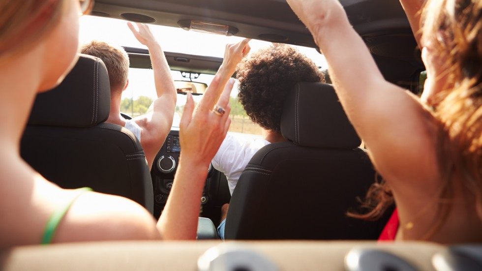 Group Of Young Friends Dancing In Back Of Open Top Car