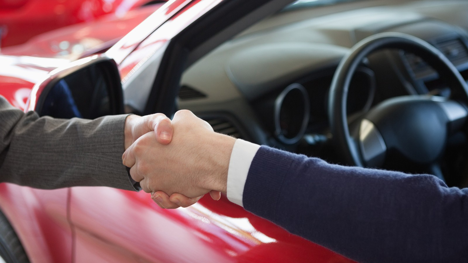 Close up of a man shaking hand to a woman in a dealership