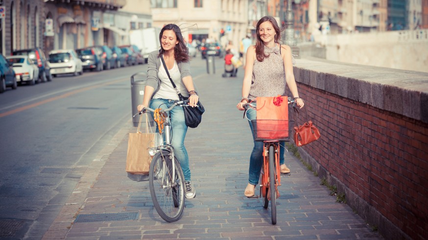 Two Beautiful Women Walking in the City with Bicycles and Bags