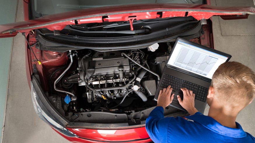 Mechanic Examining Car Engine With Help Of Laptop