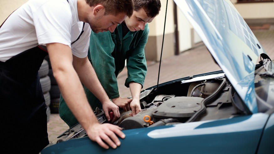 Two auto mechanics working with car