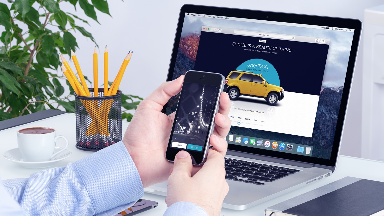 Uber app on the iPhone display in man hands and Uber website on