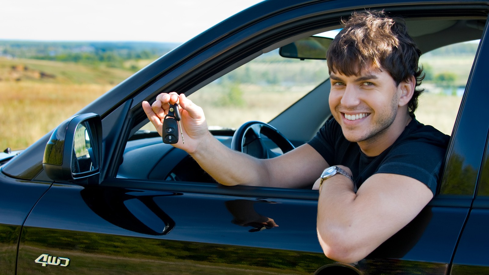 happy man showing keys in car
