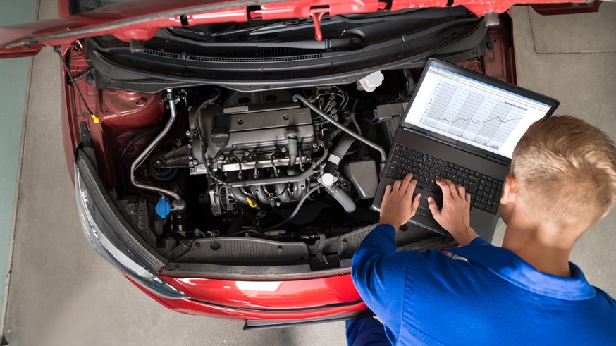 Mechanic Examining Car Engine With Help Of Laptop