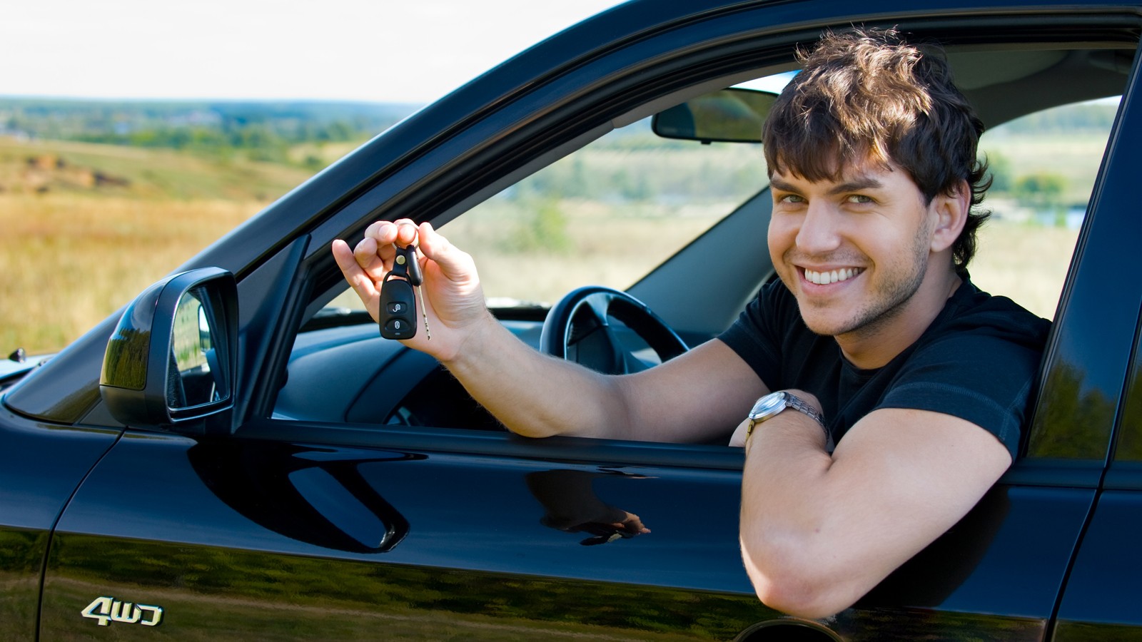 happy man showing keys in car