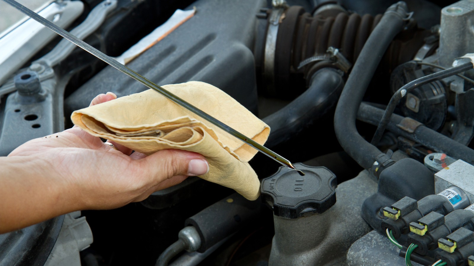 Auto mechanic checking oil