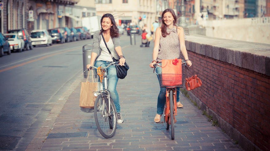 Two Beautiful Women Walking in the City with Bicycles and Bags