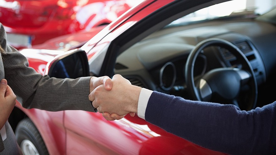 Close up of a man shaking hand to a woman in a dealership