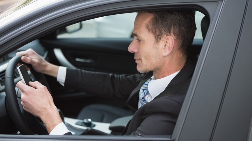 Businessman sending a text message in his car