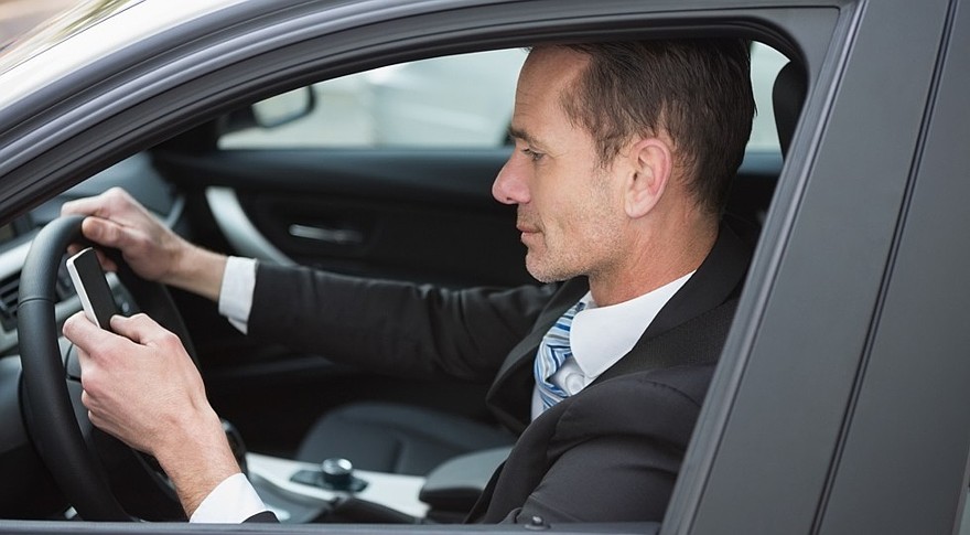 Businessman sending a text message in his car