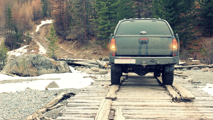 Off-road car on the old bridge into the mountain forest.