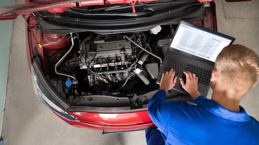 Mechanic Examining Car Engine With Help Of Laptop