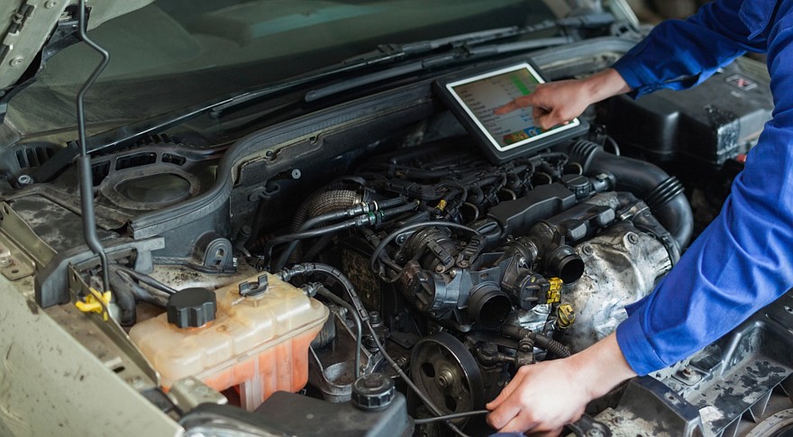 Male mechanic with digital tablet repairing car engine