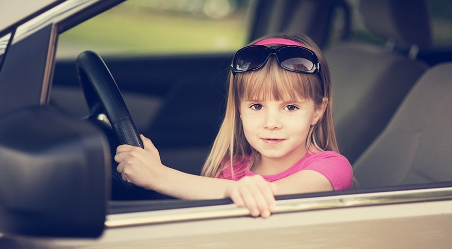 Little girl driving a car.