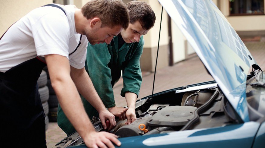 Two auto mechanics working with car
