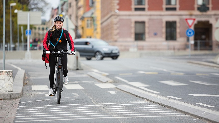 Female Cyclist With Courier Delivery Bag On Street