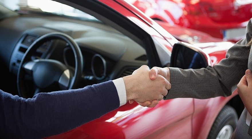 Close up of a man shaking hand to a woman in a dealership