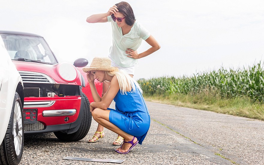 Tensed women looking at damaged cars on road against clear sky