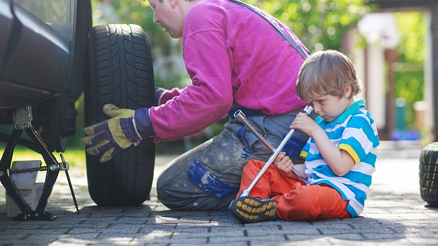 Father and adorable little boy repairing car and changing wheel