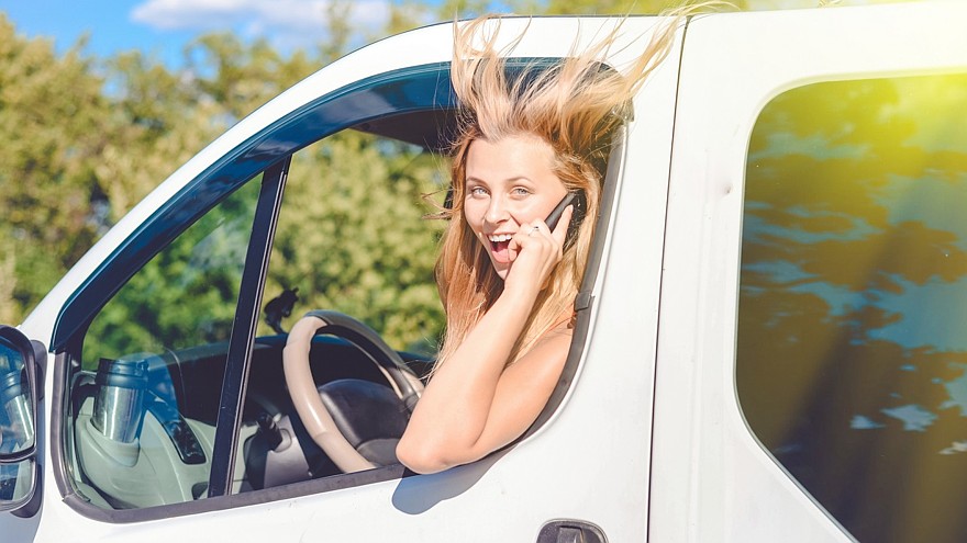 young pretty woman with phone looking from white minivan window
